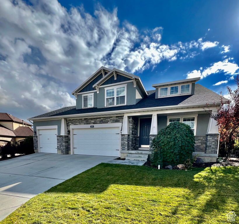 Craftsman-style home featuring a front lawn, covered porch, and a garage