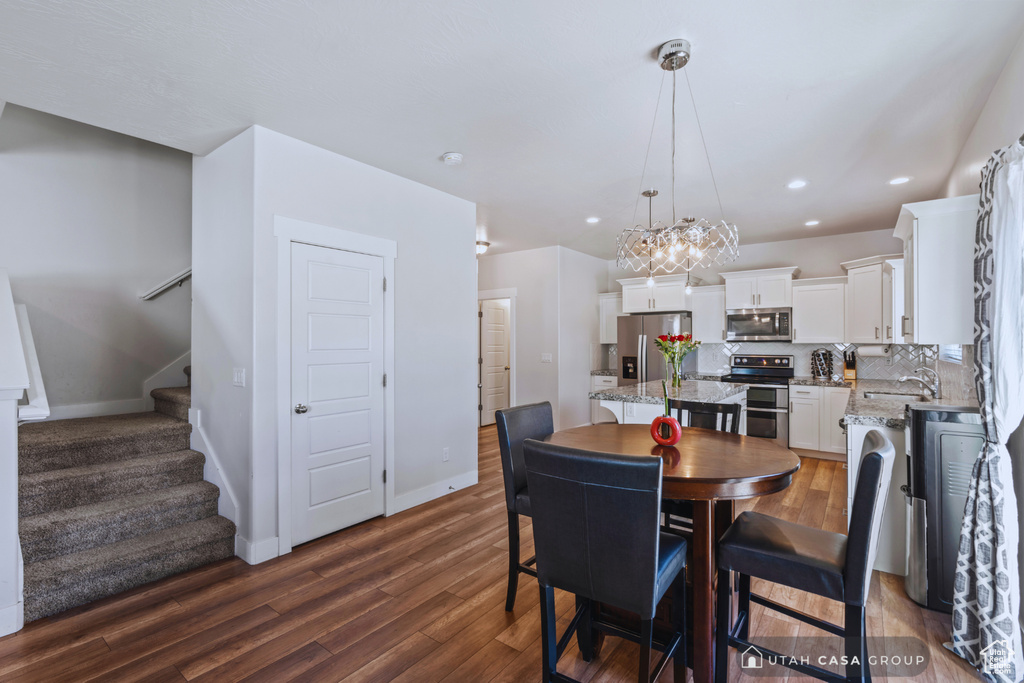 Dining area featuring sink, dark wood-type flooring, and a notable chandelier