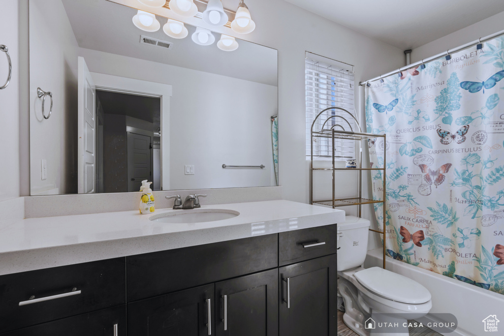 Full bathroom with vanity, shower / tub combo, and toilet