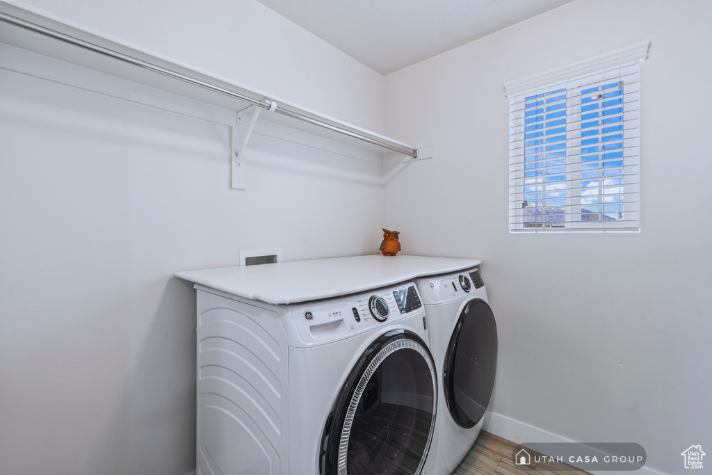 Laundry room with washer and dryer and wood-type flooring