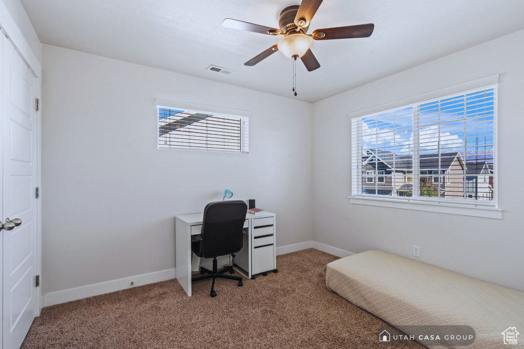 Carpeted office space featuring ceiling fan