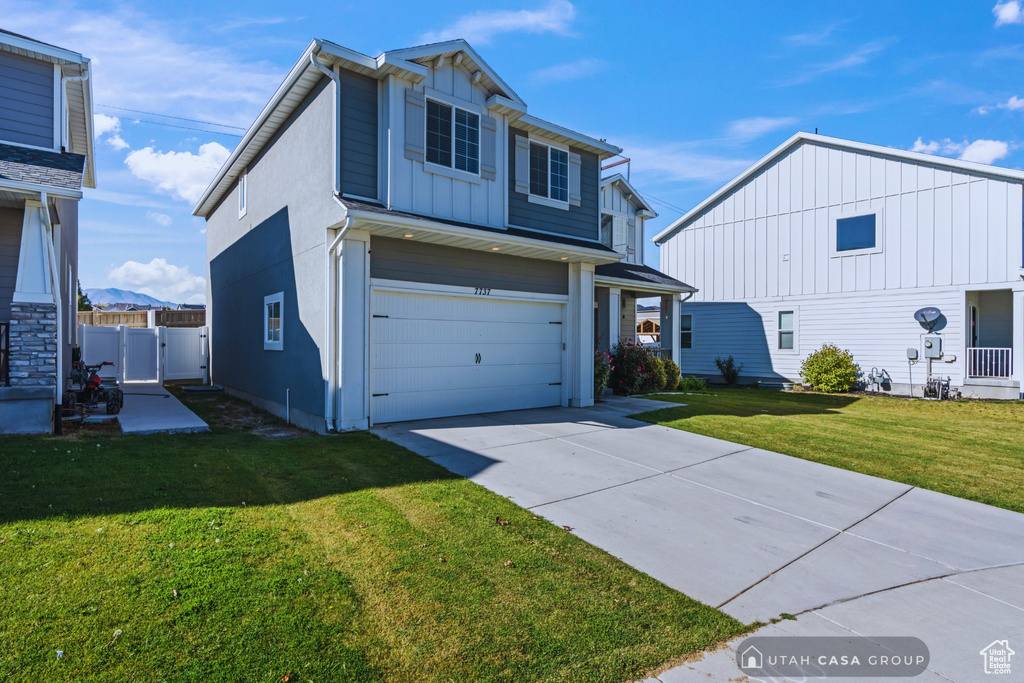 View of property featuring a front yard and a garage