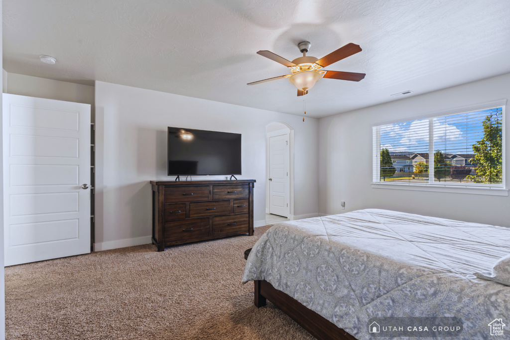 Bedroom with ceiling fan and light colored carpet