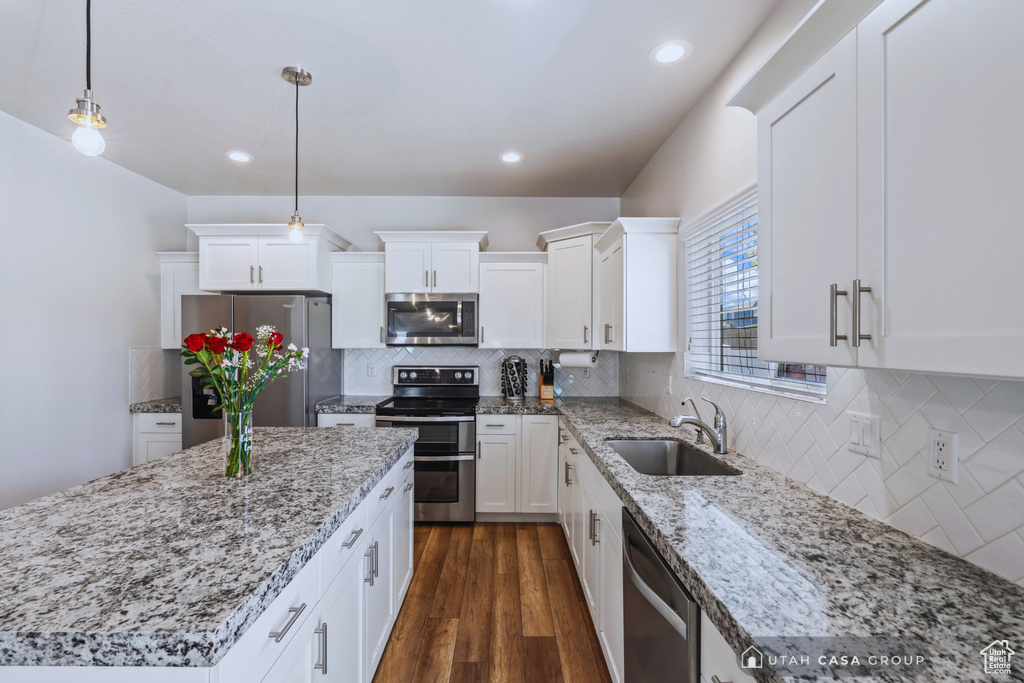 Kitchen featuring sink, stainless steel appliances, pendant lighting, white cabinets, and dark hardwood / wood-style floors