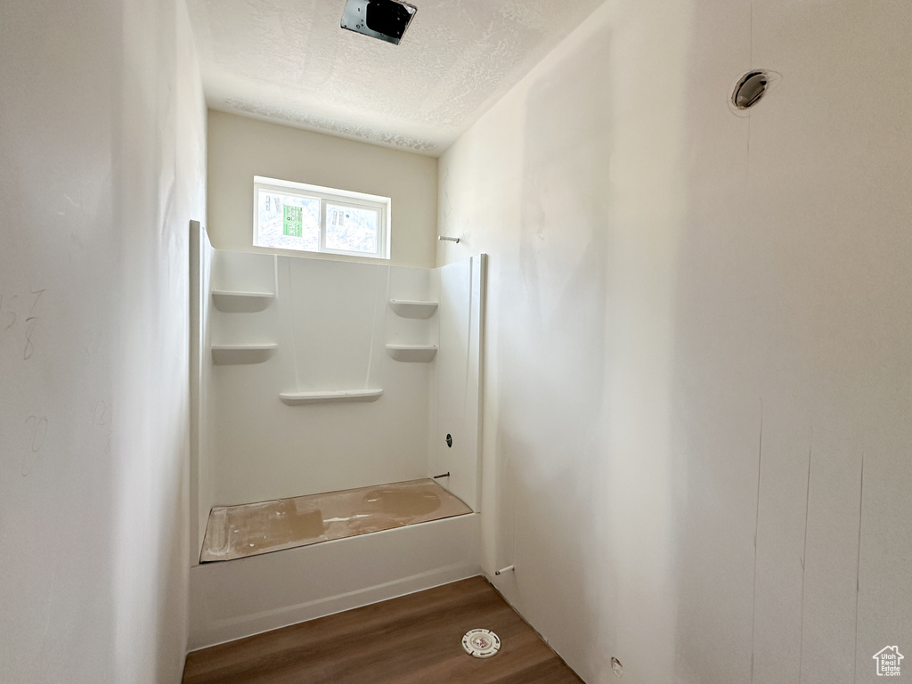 Bathroom with shower / bath combination, wood-type flooring, and a textured ceiling