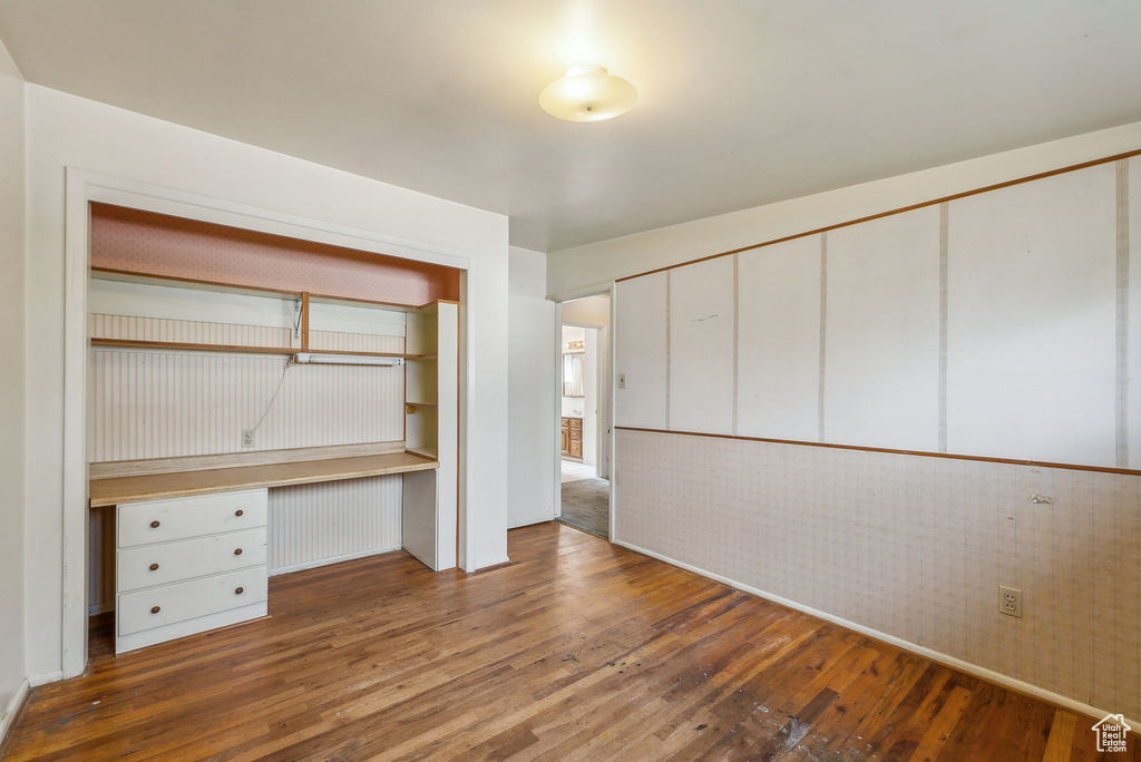 Unfurnished office featuring hardwood / wood-style flooring and built in desk