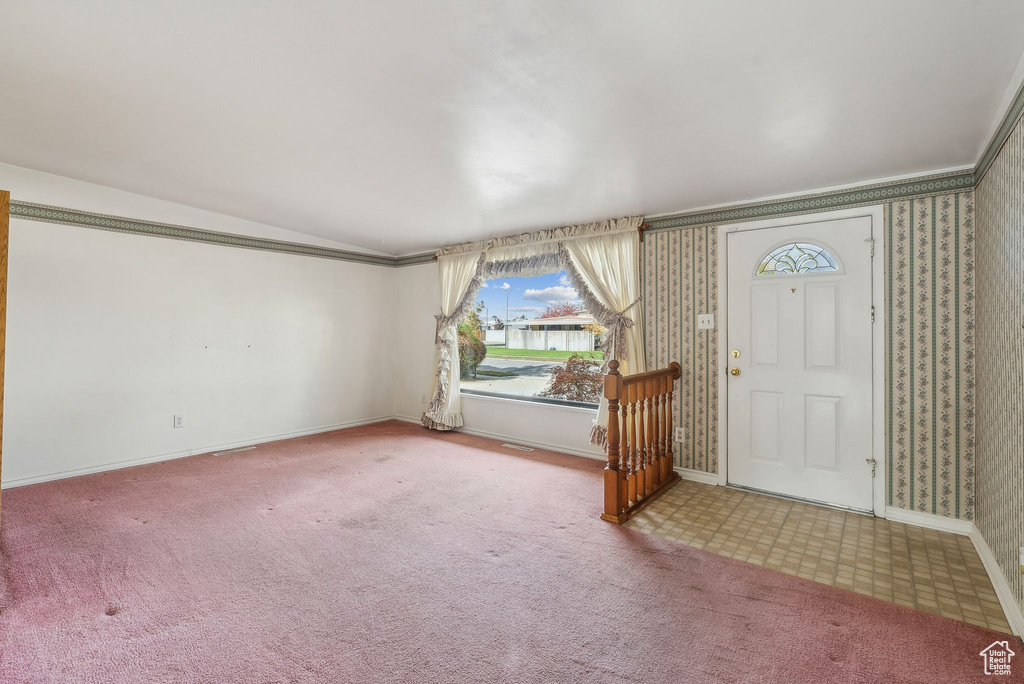 Foyer entrance featuring crown molding and carpet flooring