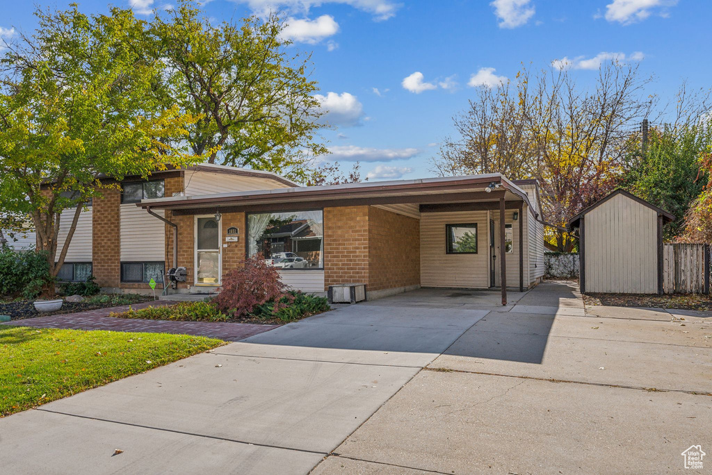 View of front of house with a carport and a storage unit