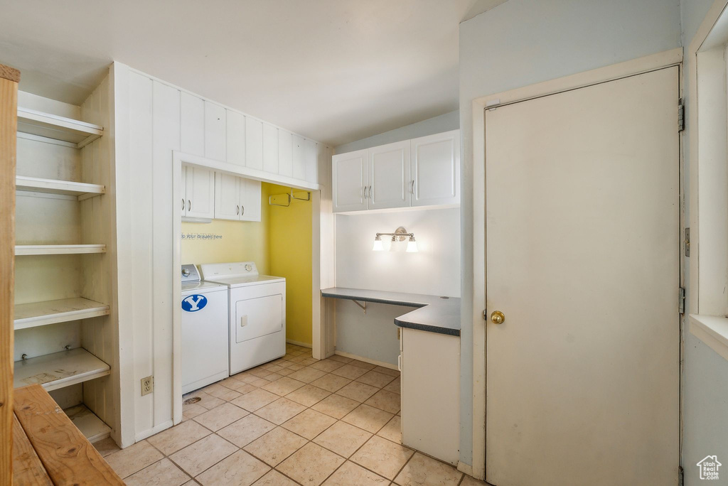 Laundry room with light tile patterned flooring, cabinets, and washer and clothes dryer