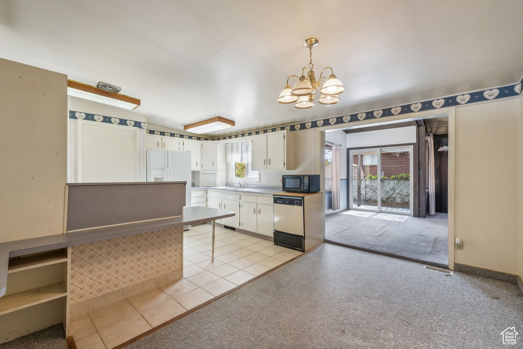 Kitchen featuring white appliances, light carpet, decorative light fixtures, and white cabinets