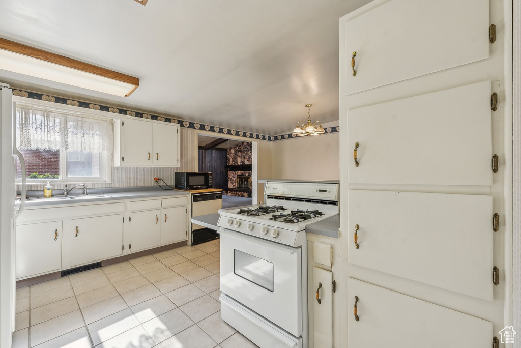 Kitchen featuring backsplash, sink, light tile patterned flooring, white cabinetry, and white appliances