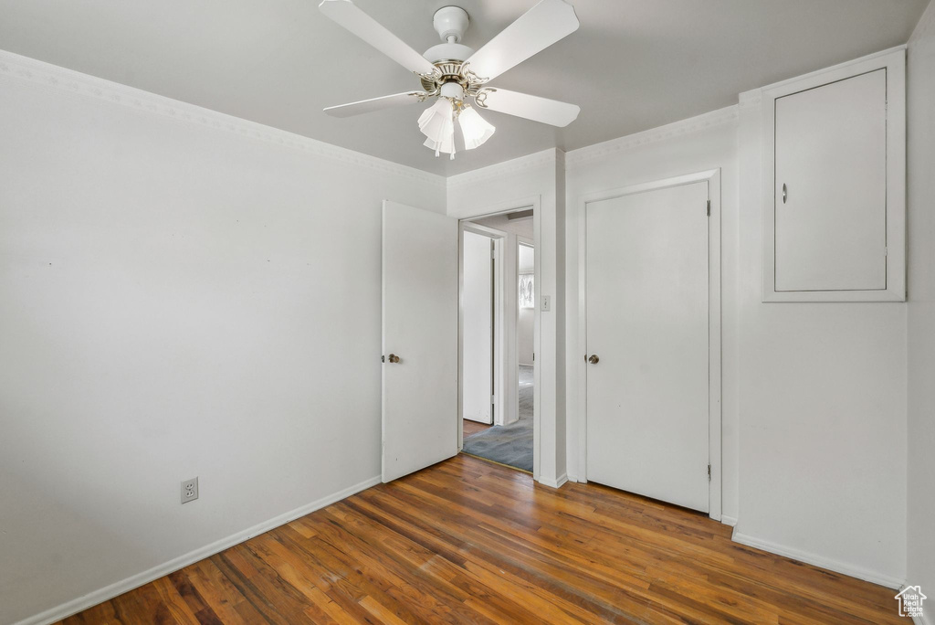 Unfurnished bedroom featuring dark wood-type flooring, ceiling fan, a closet, and ornamental molding