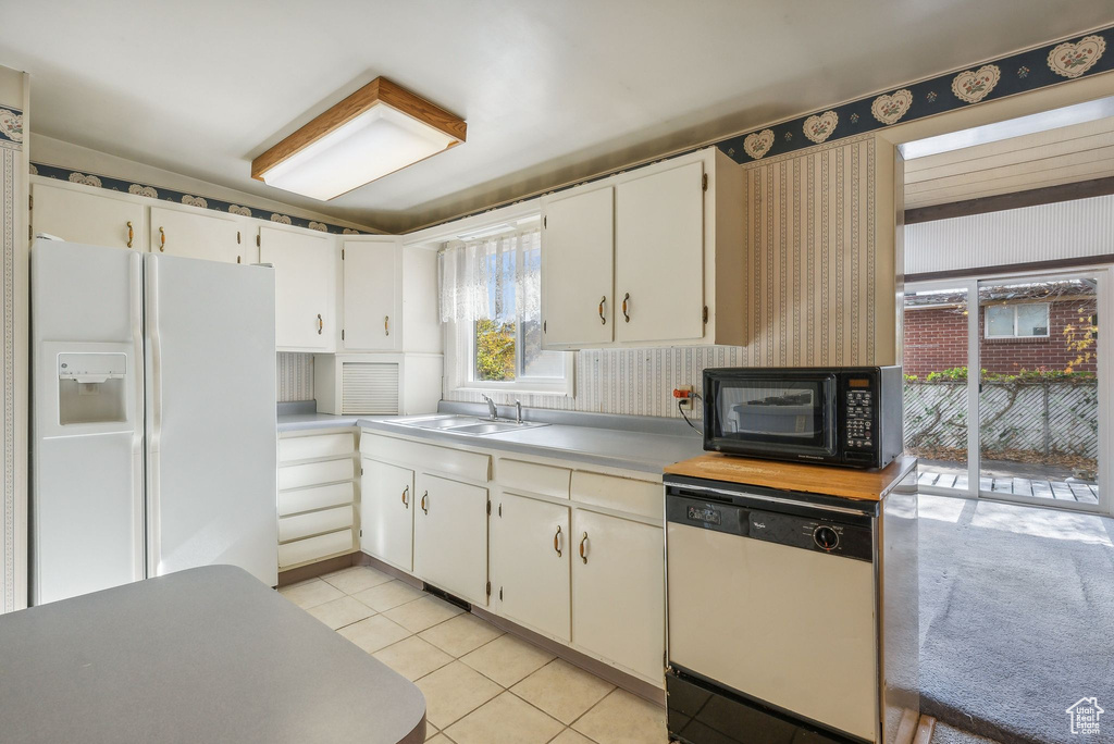 Kitchen with sink, white cabinets, white appliances, and light tile patterned floors