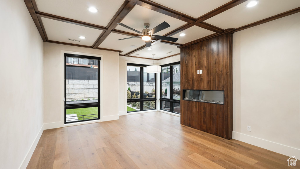 Spare room featuring crown molding, coffered ceiling, light wood-type flooring, and ceiling fan