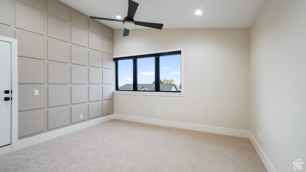 Spare room featuring vaulted ceiling, light carpet, and ceiling fan