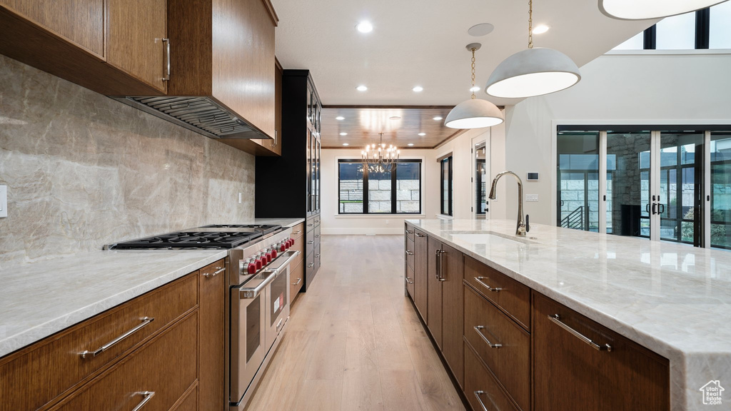 Kitchen featuring a chandelier, light hardwood / wood-style flooring, range with two ovens, pendant lighting, and sink