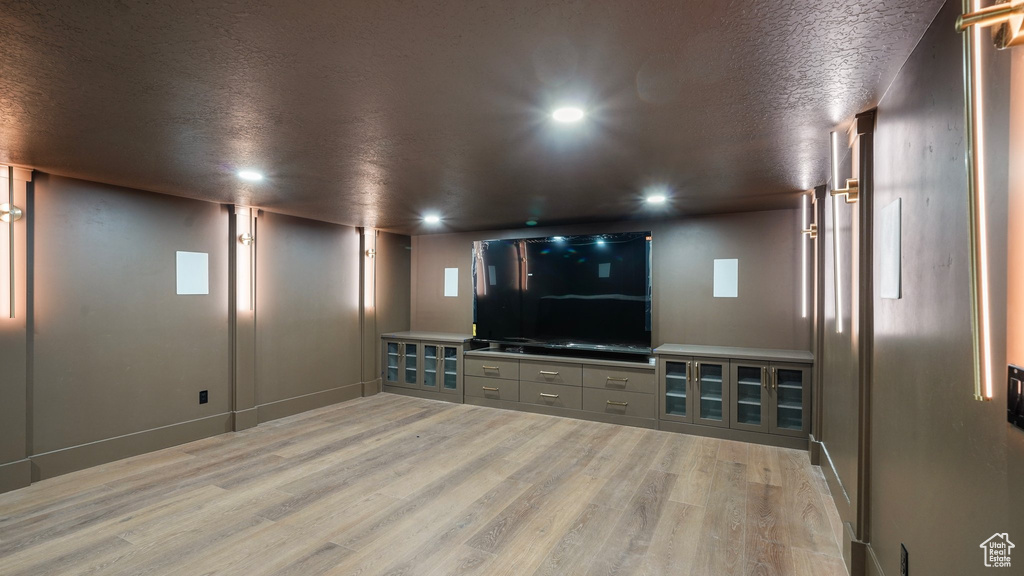 Cinema featuring light hardwood / wood-style floors and a textured ceiling