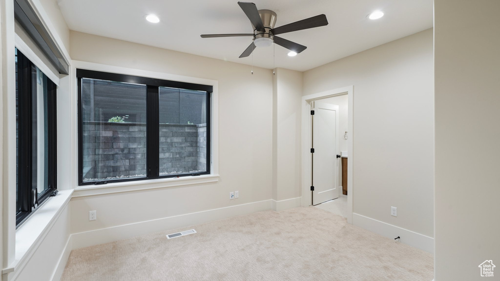 Empty room featuring light colored carpet and ceiling fan