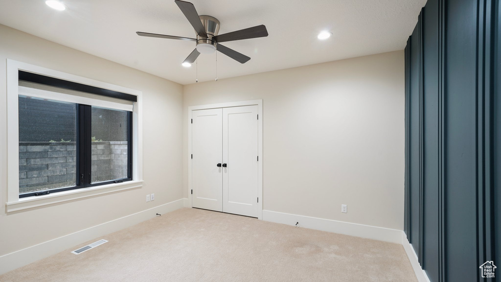 Unfurnished bedroom with light colored carpet, a closet, and ceiling fan