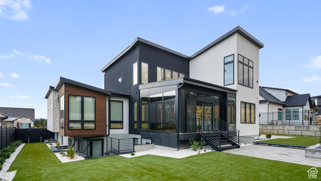 Back of property with a yard, a patio, and a sunroom