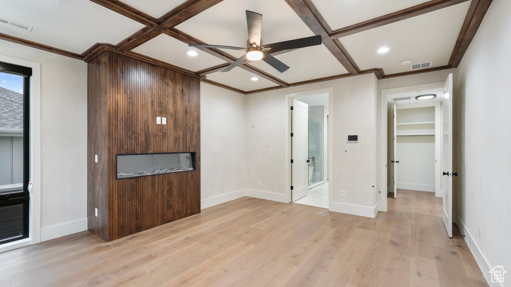 Interior space featuring ceiling fan, coffered ceiling, light hardwood / wood-style flooring, and crown molding