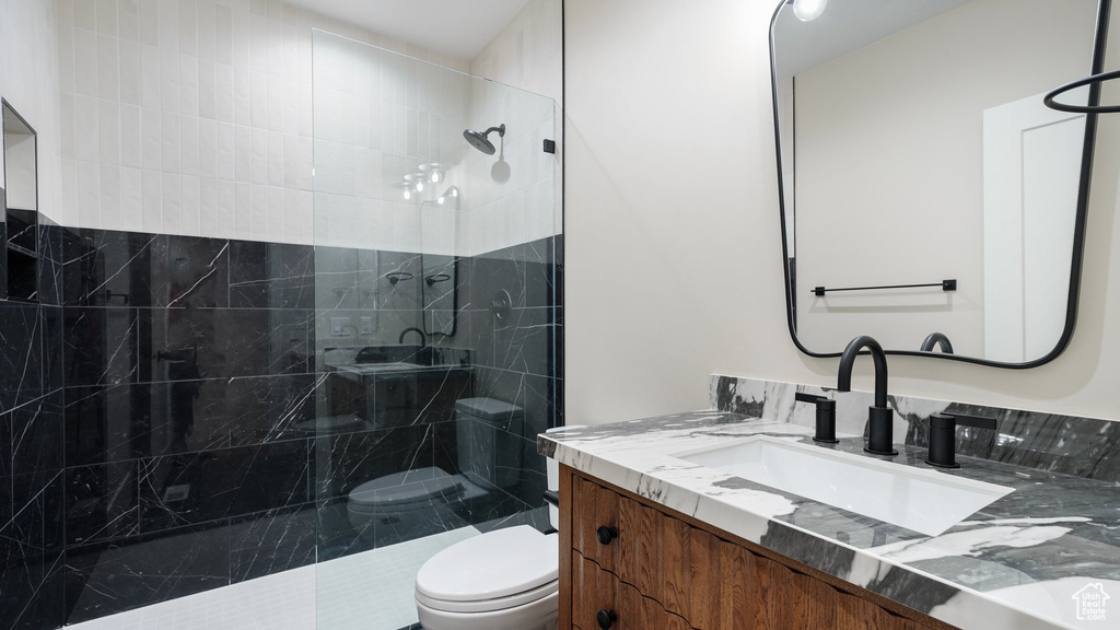 Bathroom with toilet, vanity, and tiled shower