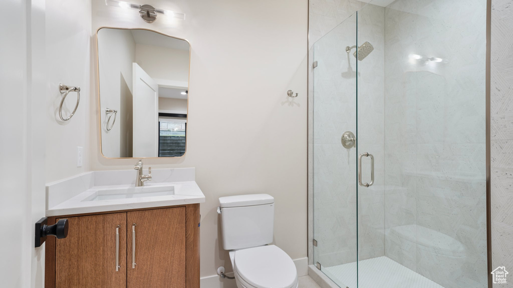 Bathroom with vanity, a shower with shower door, and toilet