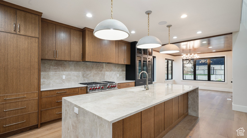 Kitchen featuring a large island, sink, high end range, and pendant lighting