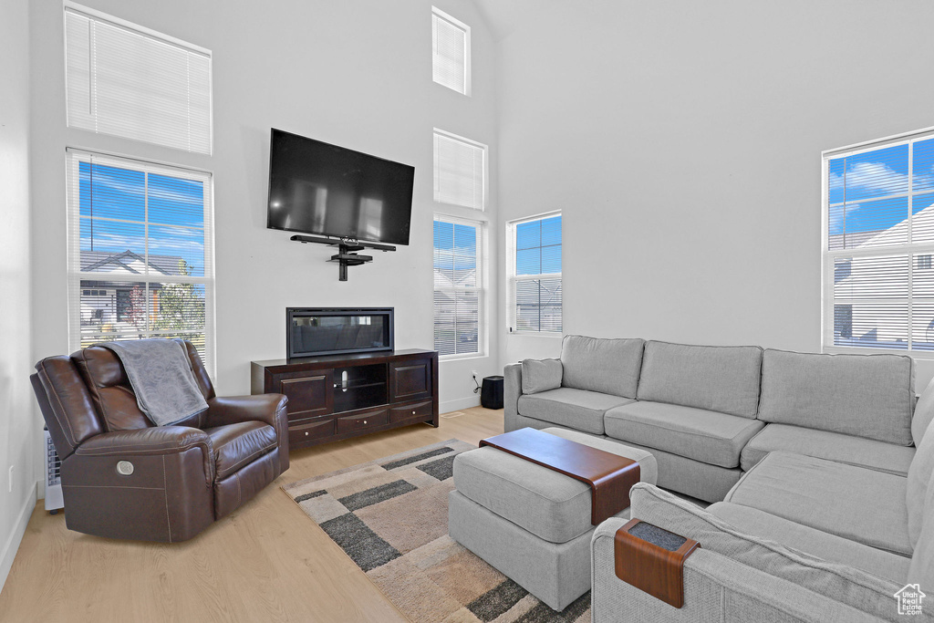 Living room with light hardwood / wood-style floors and a towering ceiling