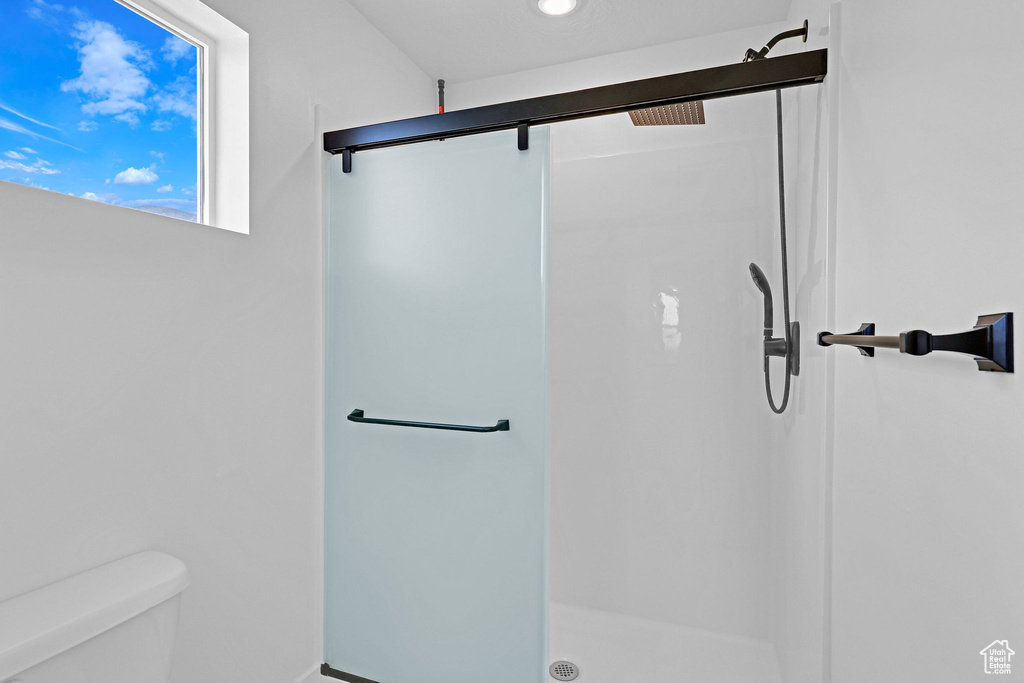 Bathroom featuring toilet and a shower with shower door