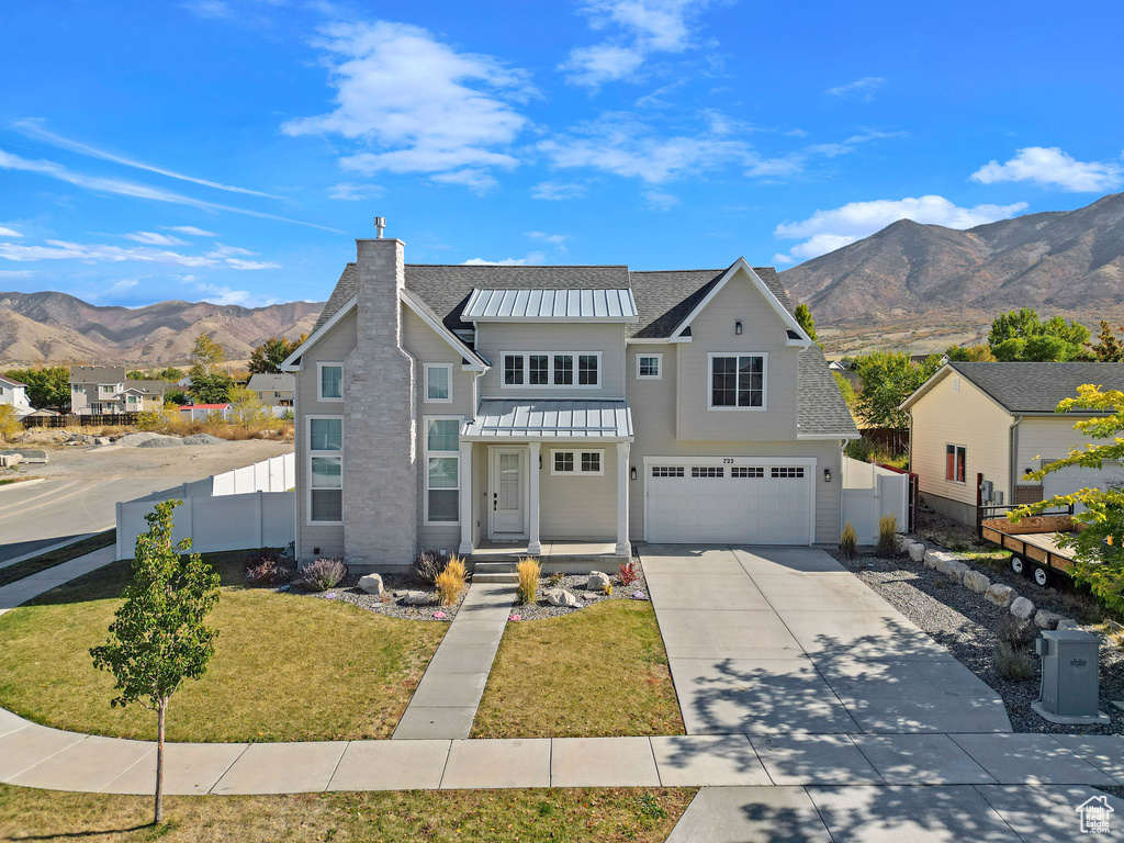 View of front of house with a mountain view, a front yard, and a garage