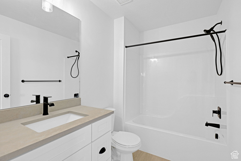 Full bathroom with toilet, hardwood / wood-style floors, vanity, and  shower combination