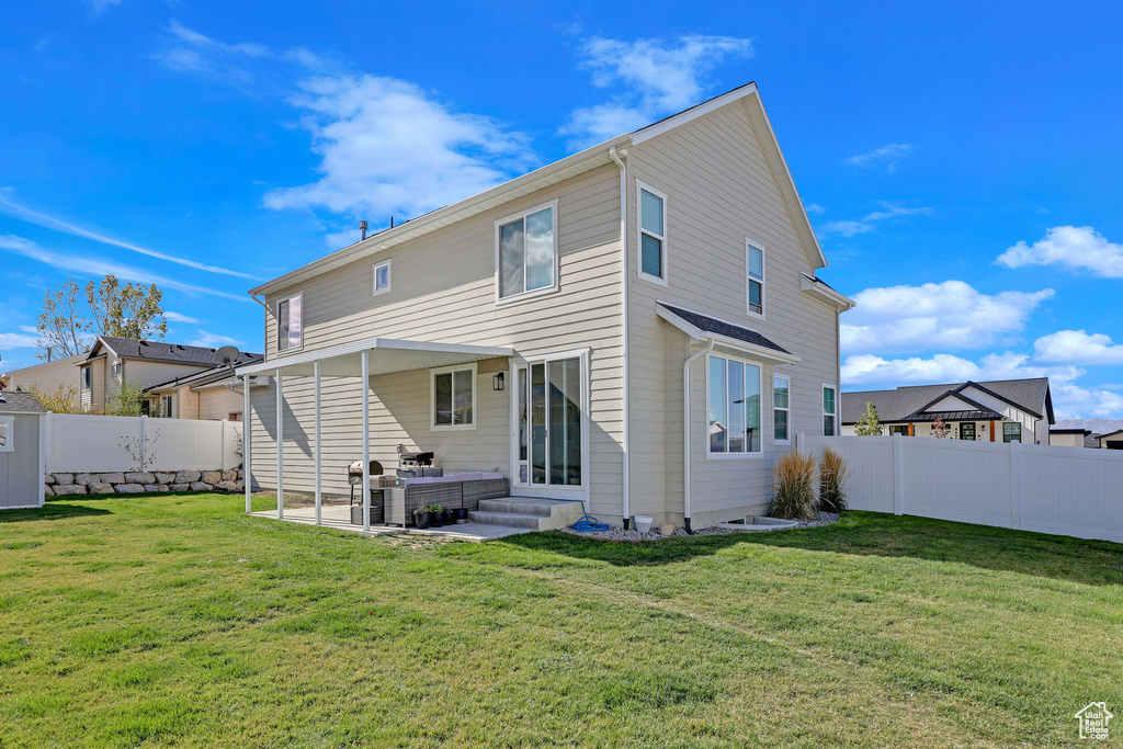 Back of house with a patio and a lawn