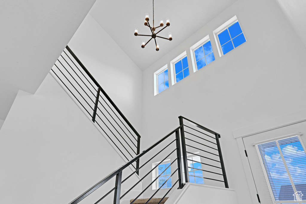 Stairs featuring a notable chandelier and high vaulted ceiling