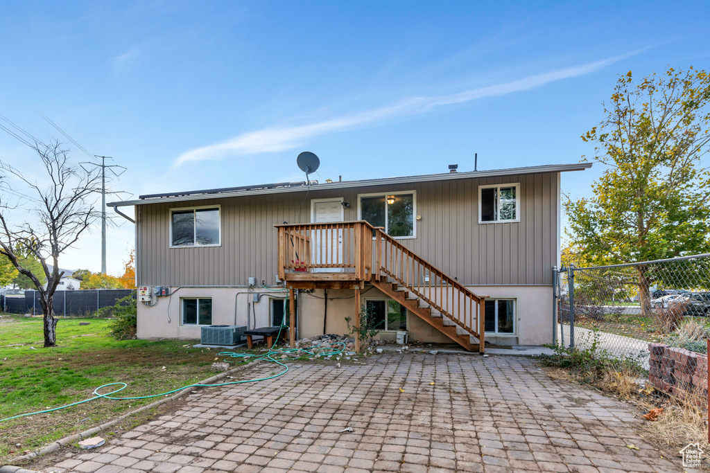 Rear view of property with central air condition unit, a patio area, and a lawn