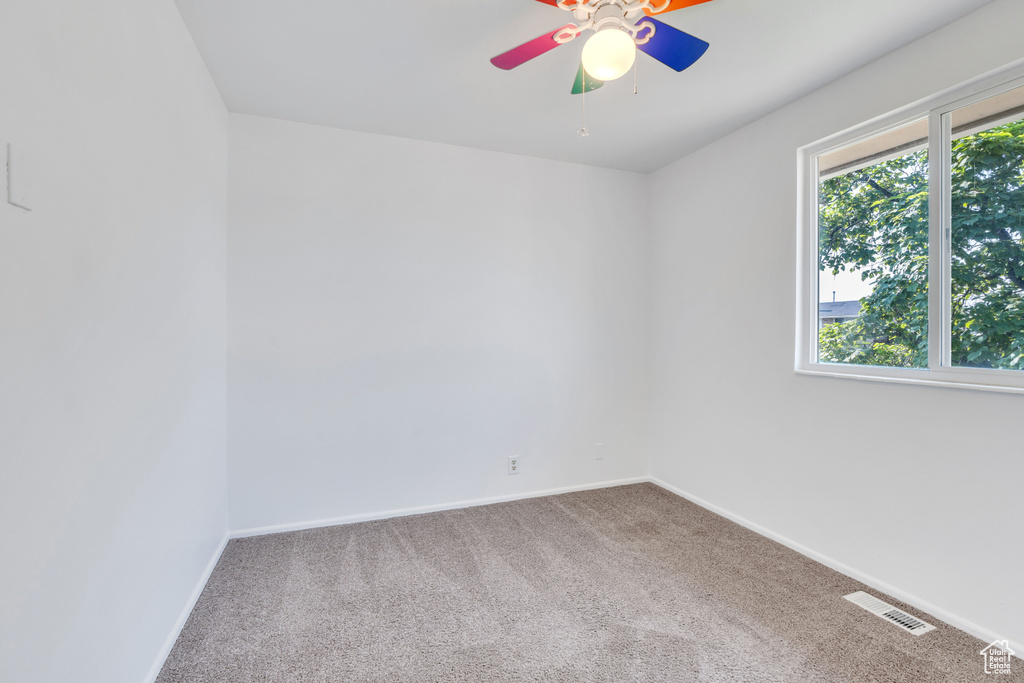 Carpeted spare room featuring ceiling fan