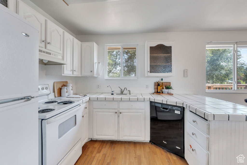 Kitchen featuring white cabinetry, a healthy amount of sunlight, ventilation hood, and white appliances