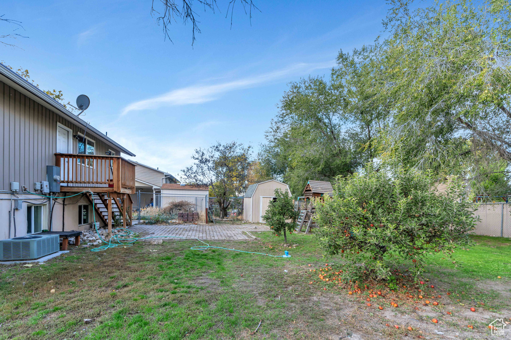 View of yard featuring a wooden deck, a storage shed, and central air condition unit