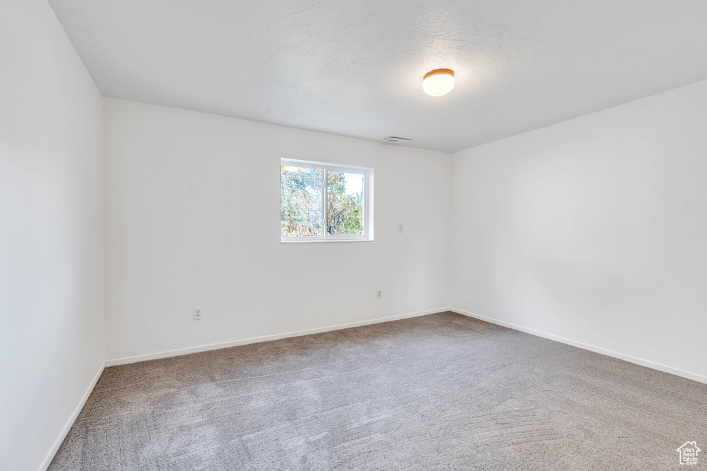 Carpeted empty room featuring a textured ceiling