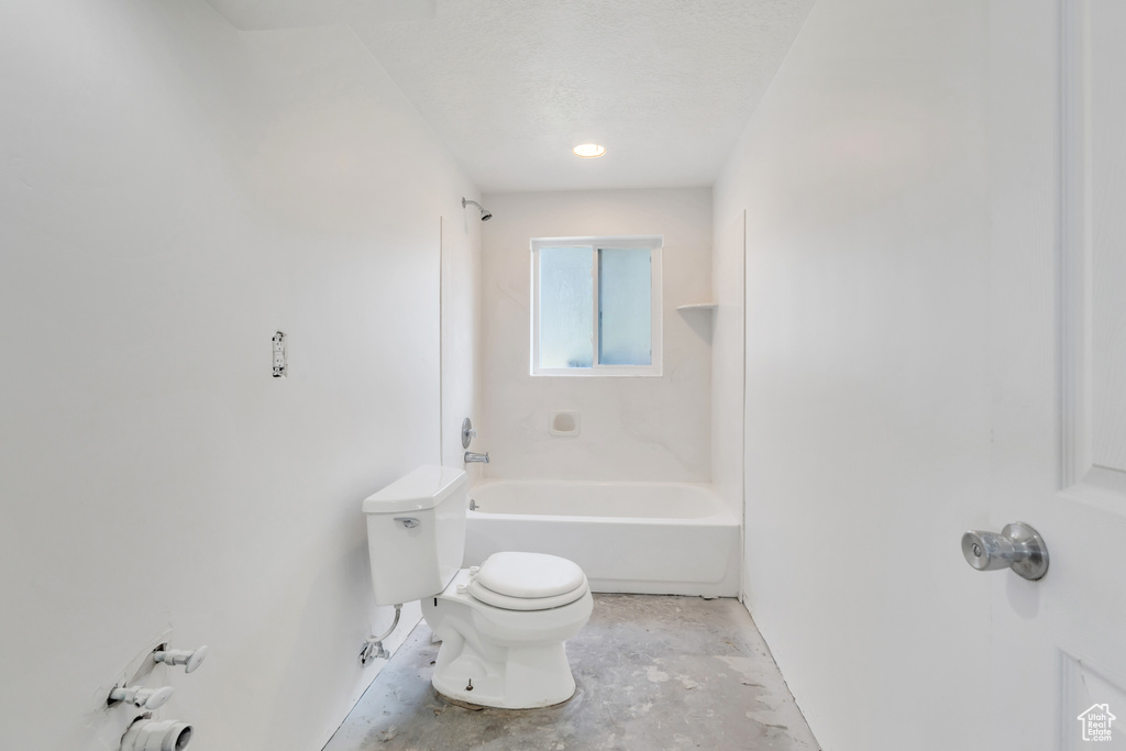 Bathroom featuring toilet, concrete floors, and washtub / shower combination