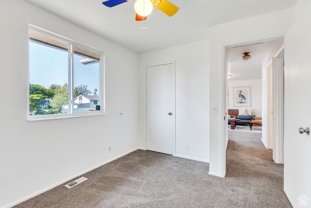 Unfurnished bedroom featuring a closet, light carpet, and ceiling fan