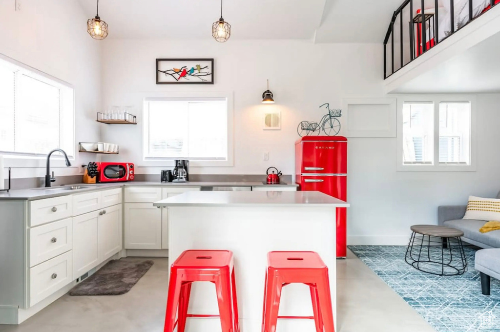 Kitchen with a breakfast bar, white cabinetry, sink, and hanging light fixtures