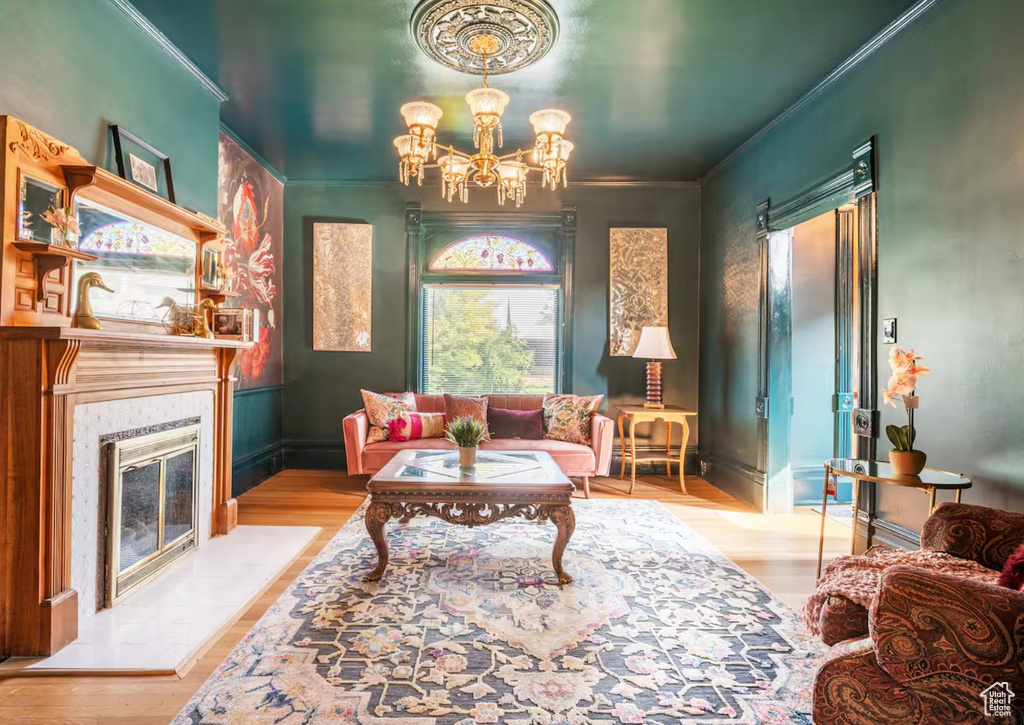 Living room with light hardwood / wood-style floors, a notable chandelier, and crown molding