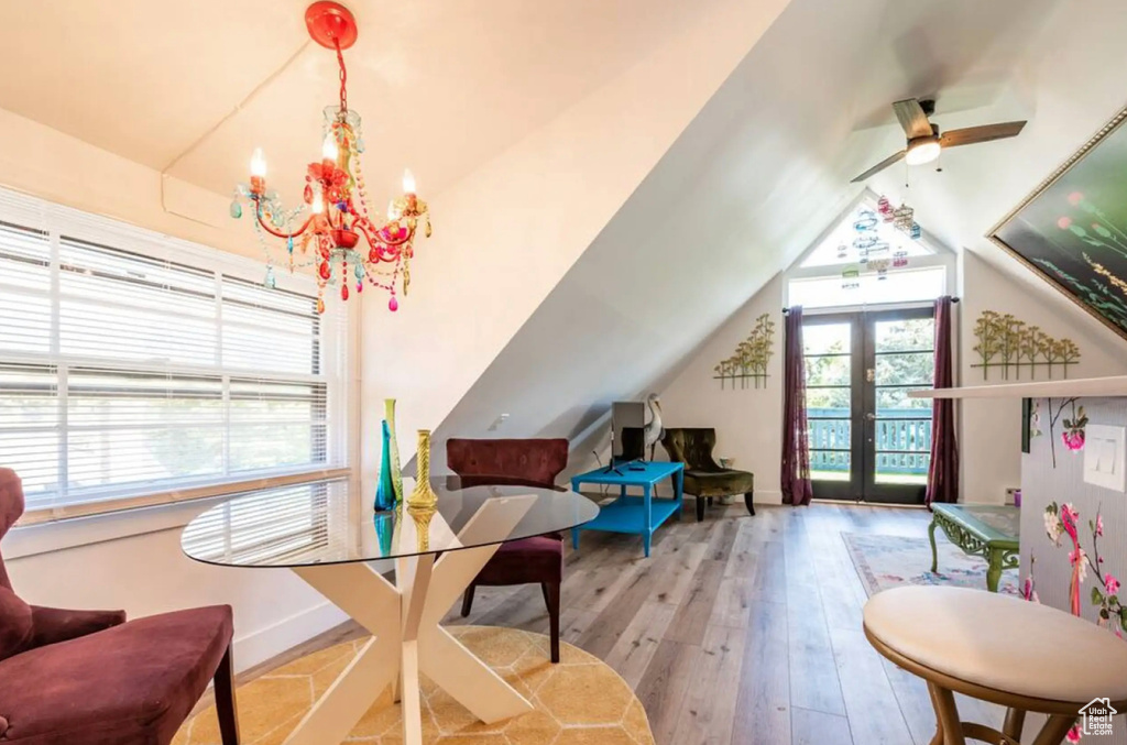 Interior space with lofted ceiling, french doors, light hardwood / wood-style flooring, and ceiling fan with notable chandelier