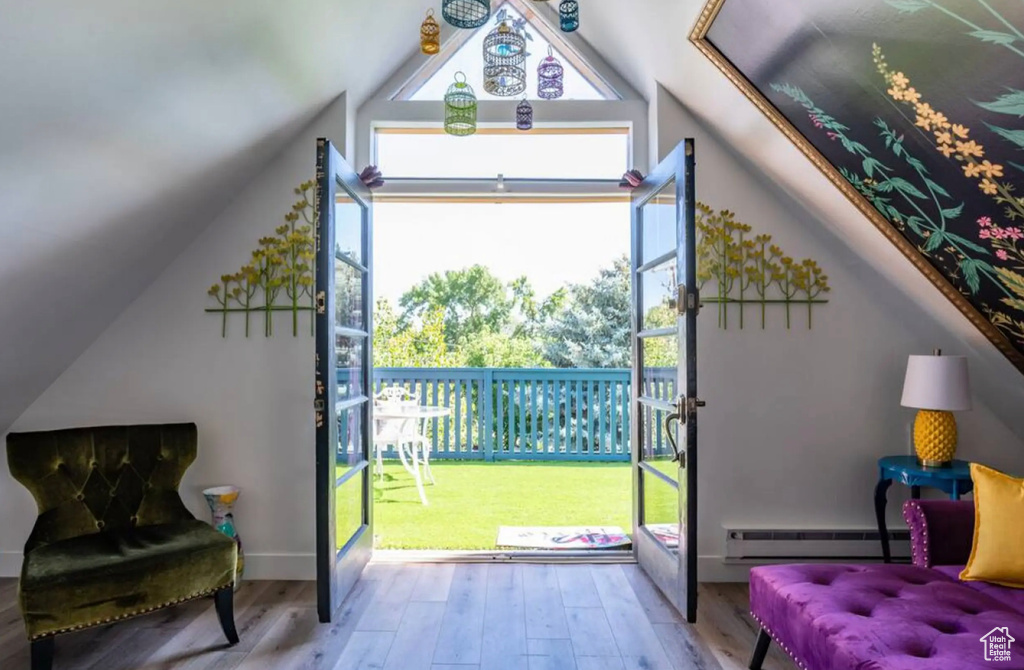 Doorway to outside with light hardwood / wood-style floors, vaulted ceiling, and baseboard heating