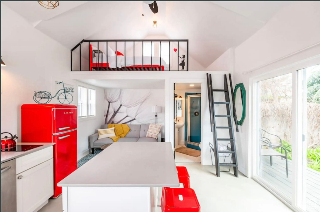 Kitchen featuring vaulted ceiling, white cabinets, light carpet, and a kitchen island