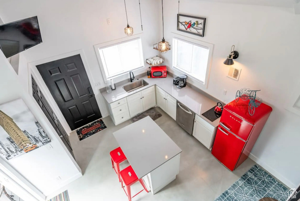 Kitchen with a towering ceiling, sink, white cabinetry, decorative light fixtures, and stainless steel dishwasher