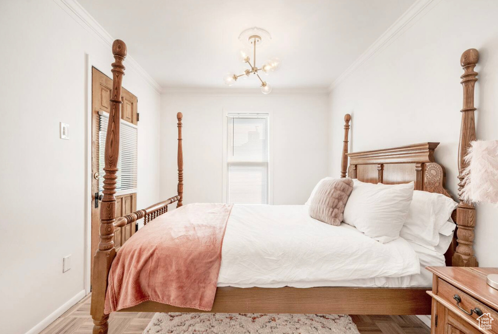 Bedroom with light parquet floors, ornamental molding, and an inviting chandelier