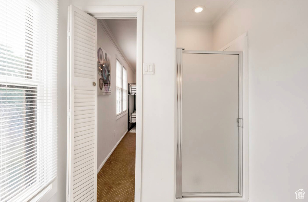 Bathroom featuring a shower with door and crown molding