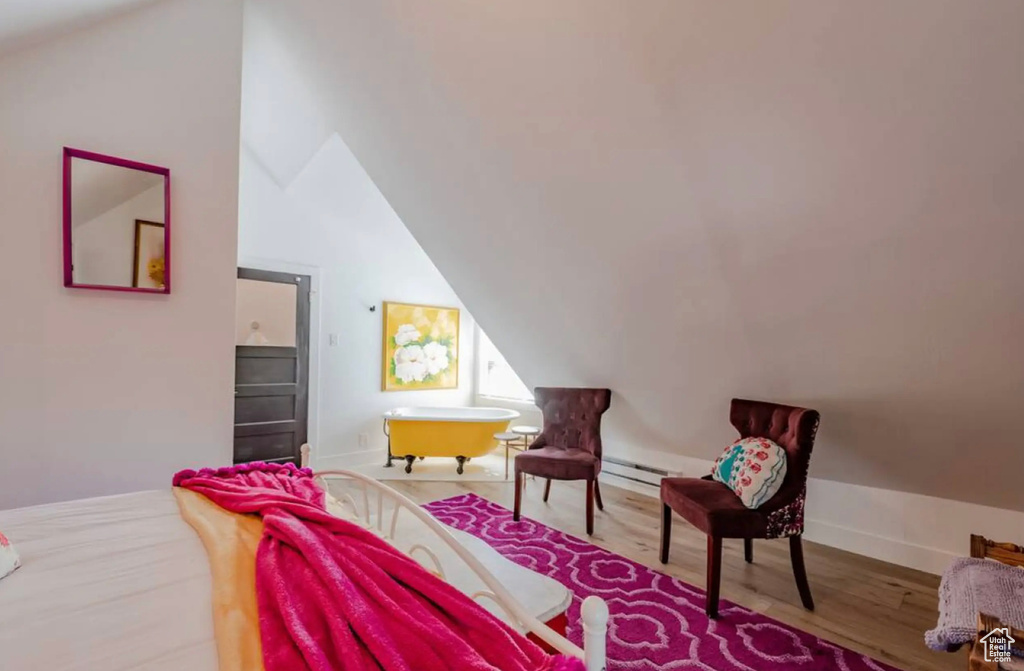 Bedroom with a baseboard heating unit, hardwood / wood-style flooring, and vaulted ceiling